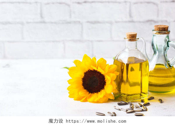 桌子上的向日葵和葵花籽油饮食和营养观念。在一张白色的厨房桌子上, 用鲜花在瓶子里配上新鲜的有机特级的向日葵油。复制空间背景